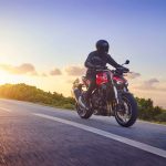 un motard qui roule avec le soleil couchant