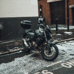 black motorcycle parked beside black metal fence during daytime