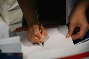 A person writing on a piece of paper with a pen